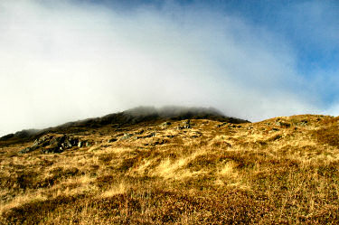 Picture of clouds moving in over the top of a hill