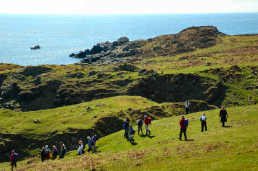 Picture of walkers near a shore approaching a deep cut from a burn