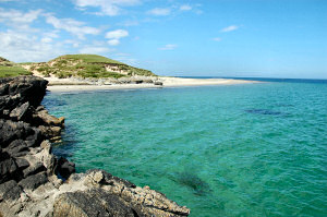 Picture of a beach below dunes, going around the top of an island