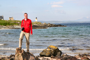 Picture of Armin standing on the beach in Port Charlotte, the lighthouse in the background
