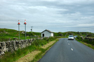 Picture of a road with two poles topped with traffic cones next to it