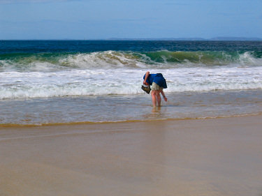 Picture of waves breaking on a beach with a man standing in the surf